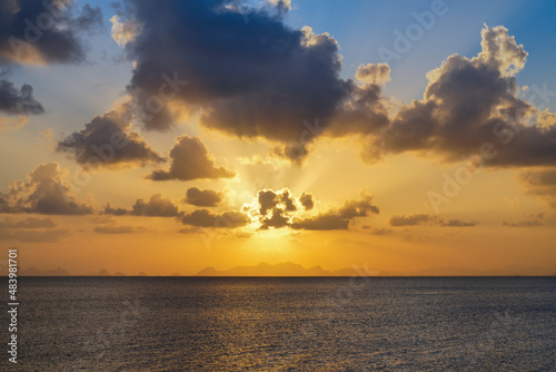 The sun behind clouds on sunset sky at the lake.