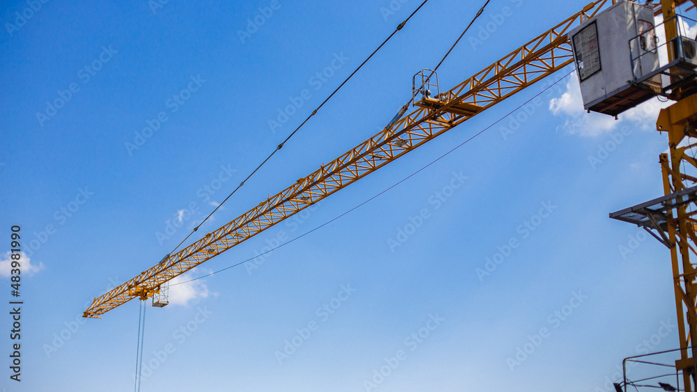 Construction cranes in blue sky at construction site.