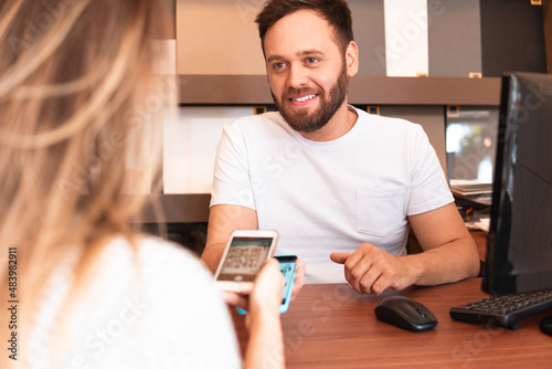 confident salesman receiving payment with qr code and mobile at counter store