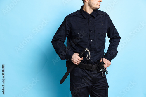 Cropped image of male policeman officer wearing black uniform with professional ammunition isolated on blue background. photo