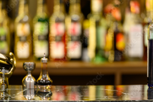 black marble table top and beautiful bokeh shelves with alcohol bottles