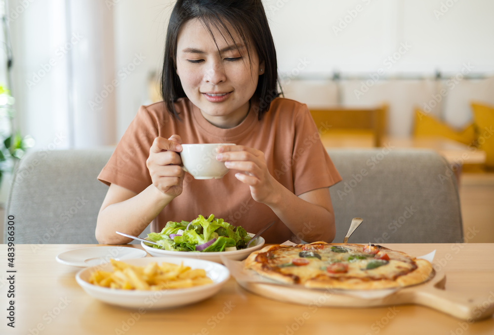 A woman drinking coffee with feeling happy and enjoy to eat food in the restaurant in leisure time. dine in the restaurant, eating delicious served hot pizza and salad. Eating concept. Italian food. A woman drinking coffee with feeling happy and enjoy to eat food in the restaurant in leisure time. dine in the restaurant, eating delicious served hot pizza and salad. Eating concept. Italian food.