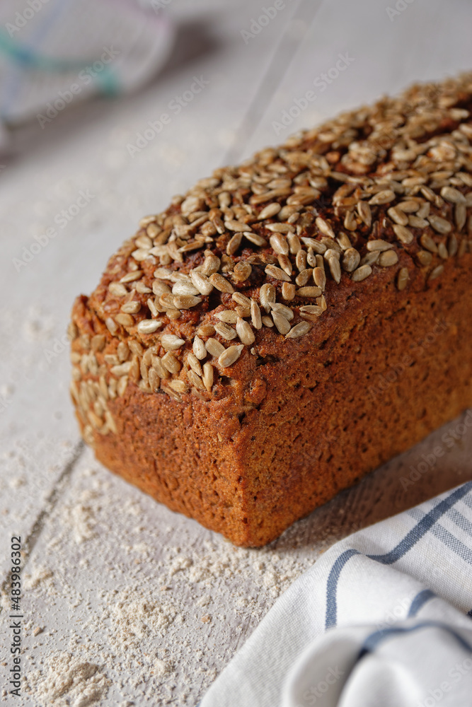 A loaf of wholemeal spelt bread, a box bread with a grain crust. Close-up view on gray wooden table. A loaf of wholemeal spelt bread, a box bread with a grain crust. Close-up view on gray wooden table.