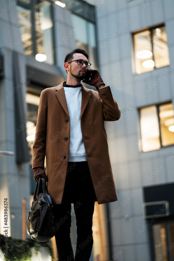 portrait of a young businessman talking on the phone near the office portrait of a young businessman talking on the phone near the office