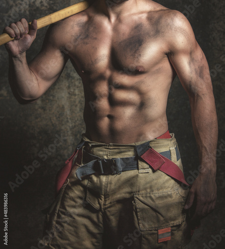 Firefighter with a sexy muscular body holding his axe