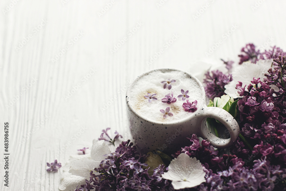 Delicious coffee with lilac petals, rose and lilac branch on rustic white wooden background. Hello spring. Space for text. Happy mothers day. Good morning still life Delicious coffee with lilac petals, rose and lilac branch on rustic white wooden background. Hello spring. Space for text. Happy mothers day. Good morning still life