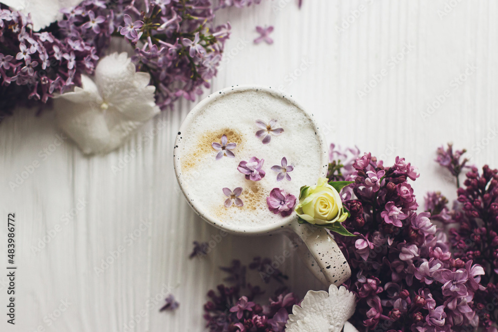 Delicious coffee with lilac petals and lilac branch on rustic white wooden background flat lay. Happy mothers day. Good morning. Hello spring. Space for text Delicious coffee with lilac petals and lilac branch on rustic white wooden background flat lay. Happy mothers day. Good morning. Hello spring. Space for text