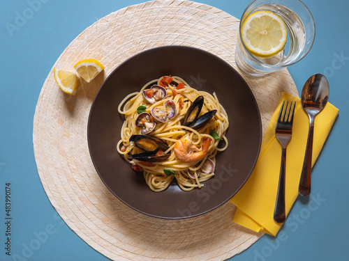 Dish of spaghetti allo scoglio top view. Spaghetti with seafood on blu background. Italian food, pasta with shrimps and mussels, clams. Mediterranean carb diet.