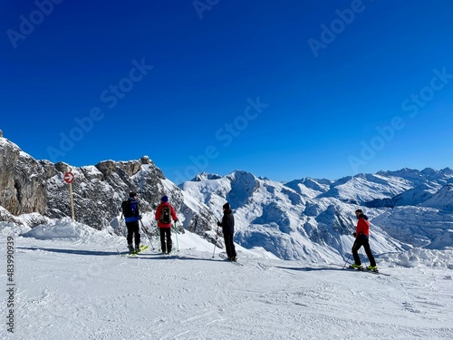 Skiers taking a break and looking at pistes, ski slopes and mountains of noble skiing resort Lech Zuers, part of the Arlberg ski area. Vorarlberg, Austria.