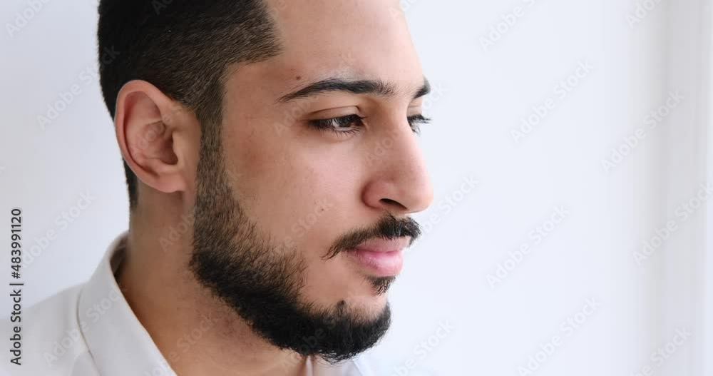 Young man smiling and looking out through window at office Young man smiling and looking out through window at office