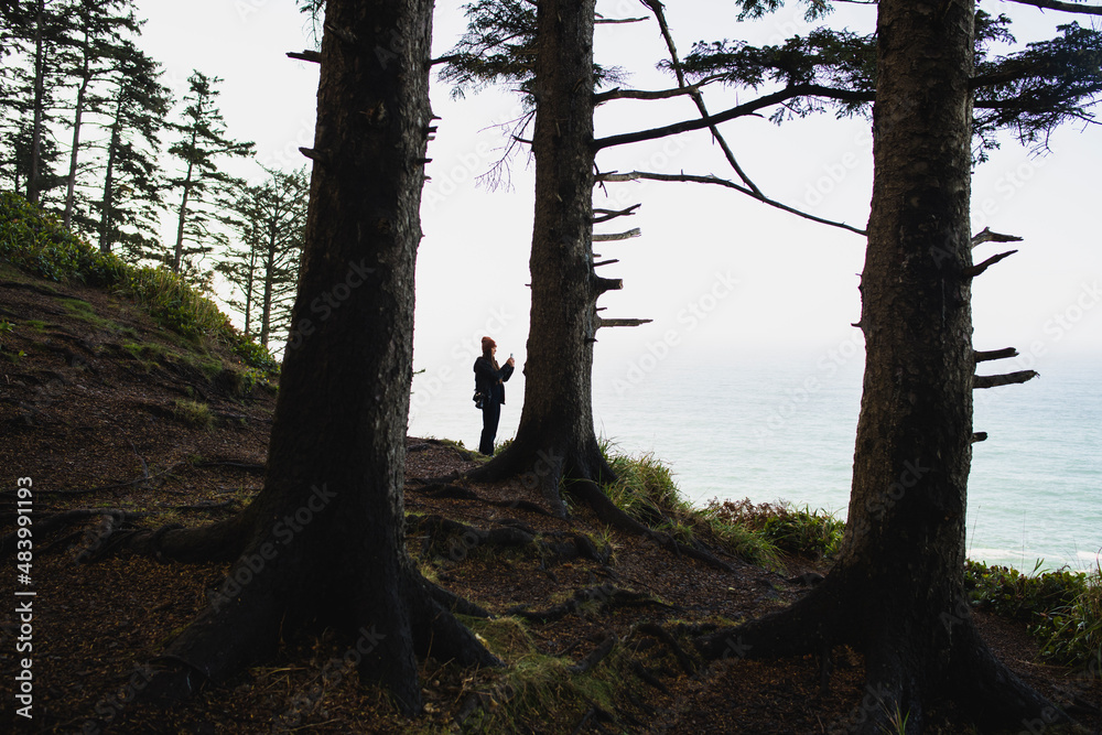 Solo Woman photographing with her phone in coastal Oregon Solo Woman photographing with her phone in coastal Oregon