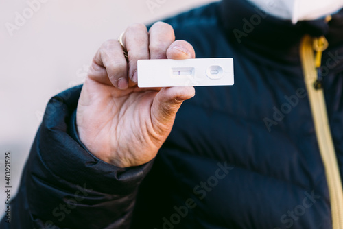 Detail of the hand of an elderly woman in the street holding a negative antigen test. Concept covid-19, ihu, delta, omicron, detection test and pandemic. photo