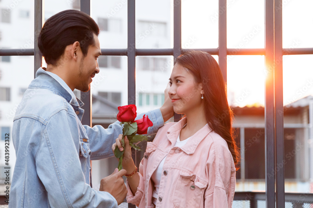 young happy couple love and romantic at first date relationship. asian teenage woman surprise and smiling at boyfriend gives red rose flowers at dinner in valentine day. couple and happiness concept. young happy couple love and romantic at first date relationship. asian teenage woman surprise and smiling at boyfriend gives red rose flowers at dinner in valentine day. couple and happiness concept.
