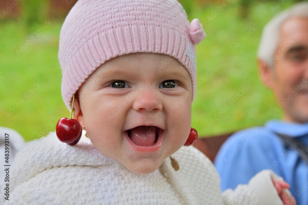 Laughing baby face with red cherries in the ears Laughing baby face with red cherries in the ears