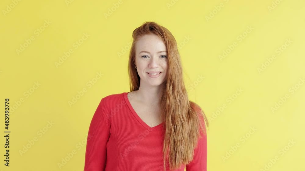 Portrait of red-haired woman on yellow background. female looks into camera and smiles. Good mood. Portrait of red-haired woman on yellow background. female looks into camera and smiles. Good mood.