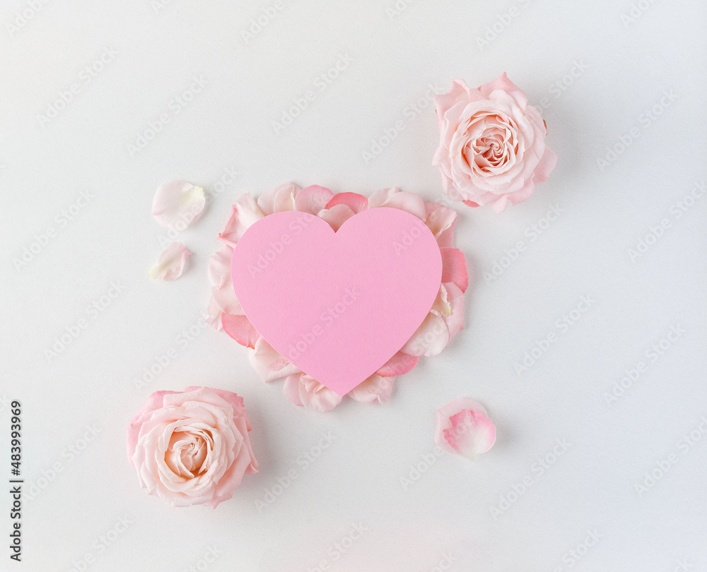 Valentine's Day background. Creative layout with pink flowers, paper heart over punchy pastel background. Top view, flat lay. Spring, summer or garden concept. Present for Woman day. Valentine's Day background. Creative layout with pink flowers, paper heart over punchy pastel background. Top view, flat lay. Spring, summer or garden concept. Present for Woman day.