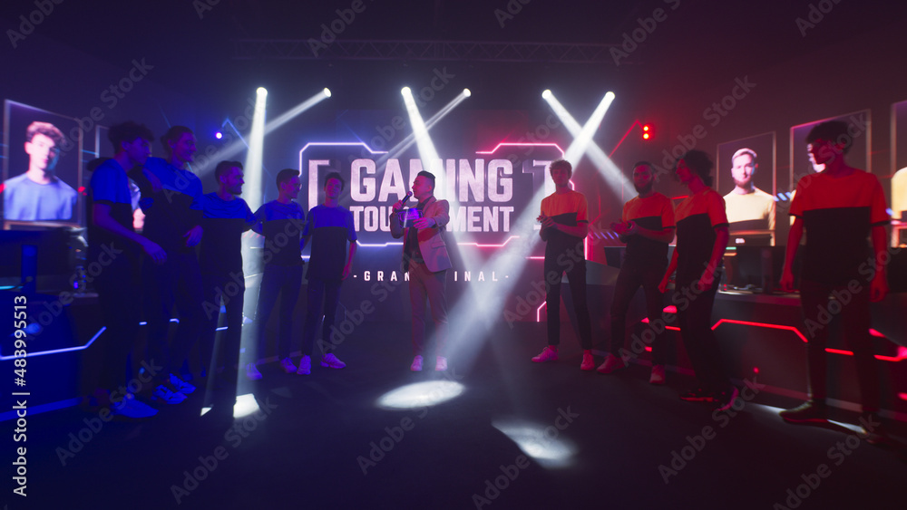Group of teammates esport gamers walking and clapping hands then standing in front of monitor with gaming tournament banner at start of championship. - obrazy, fototapety, plakaty 
