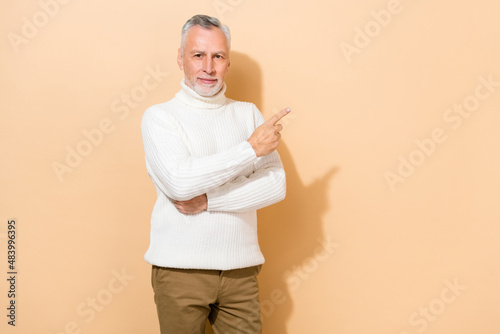 Portrait of attractive content grey-haired man demonstrating copy empty blank space ad isolated over beige pastel color background