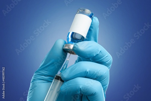 Hand in medical gloves holding a vaccine vial with Covid 19 Vaccine Booster text, for Coronavirus booster shot. photo