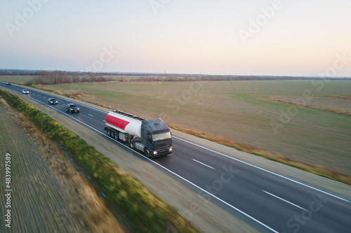 Aerial view of blurred fast moving fuel cargo truck driving on highway hauling goods. Delivery transportation and logistics concept