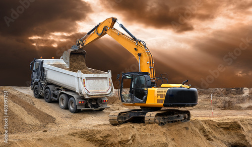 excavator working on construction site in front of dramatic sky