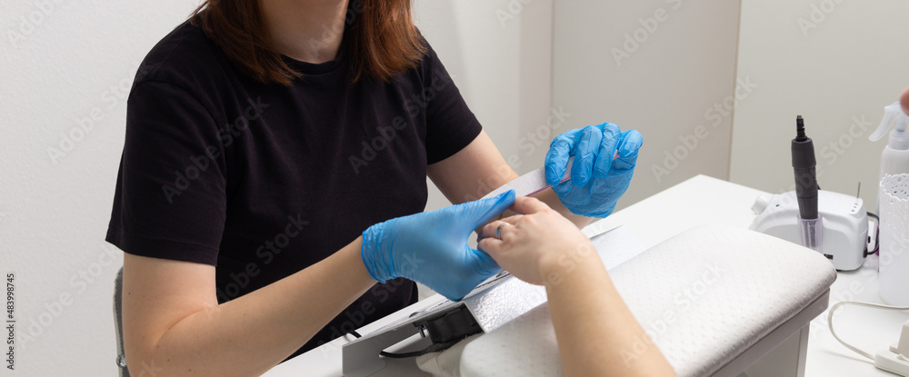 The master in the beauty salon makes the girl a manicure. The master in the beauty salon makes the girl a manicure.