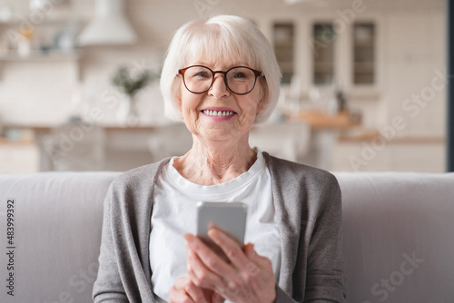 Closeup cropped front view photo of senior old elderly caucasian woman grandmother using smart phone cellphone for e-banking e-commerce, surfing social media online at home photo
