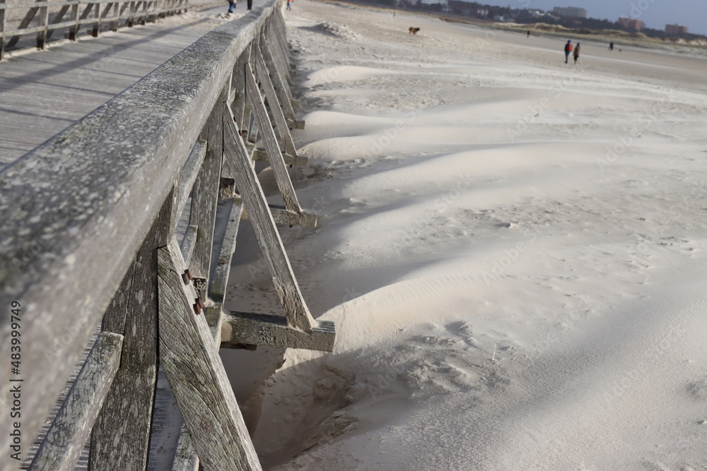 Obraz premium Vom Wind aufgeschütteter Strandsand an der Seebrücke von Sankt Peter Ording