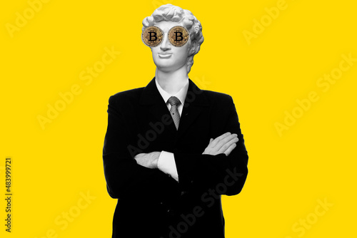 Abstract modern collage. The man with the plaster head of David Smiling businessman standing with arms folded with bitcoin eyes isolated on yellow background photo