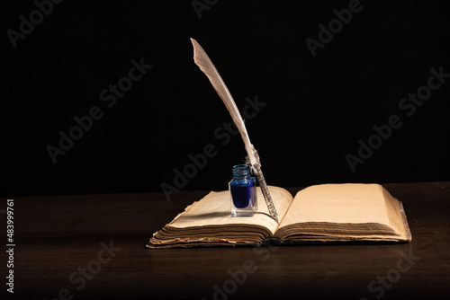 Tableau sur toile Quill pen and inkwell resting on an old book concept for literature, writing, au