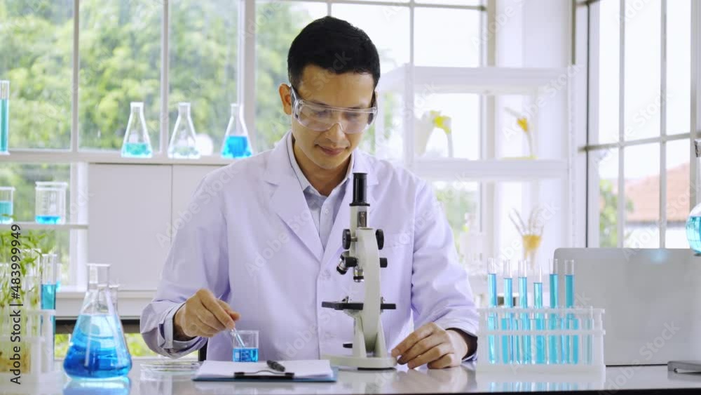 Asian male scientist working research for science lab. microscope is used to detect virus in production of vaccines for treatment of diseases such as new strain of covid-19. treatment technology Asian male scientist working research for science lab. microscope is used to detect virus in production of vaccines for treatment of diseases such as new strain of covid-19. treatment technology