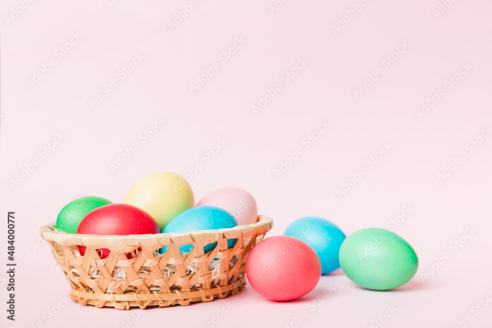 Multi colors Easter eggs in the woven basket on colored background . Pastel color Easter eggs. holiday concept with copy space