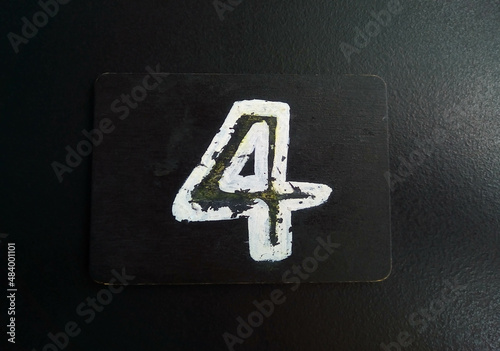 The number 4 is written in white on a black plate lying on a black table