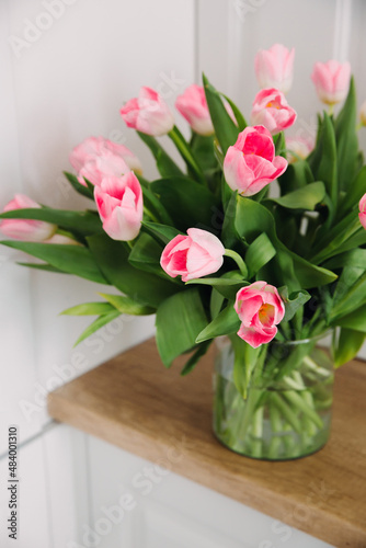 Bouquet of pink tulips in a transparent vase on the kitchen table. International Women s Day 8 March. Selective focus.