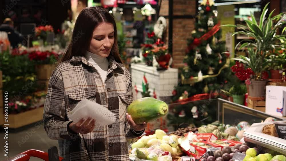 Pretty young woman in the fruit section of the supermarket chooses papaya. Pretty young woman in the fruit section of the supermarket chooses papaya.