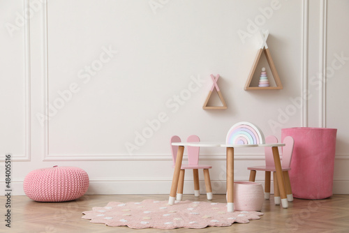 Photo Cute child room interior with furniture, toys and wigwam shaped shelves on white
