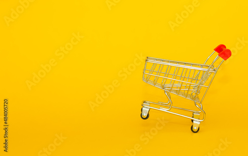 Metal basket for groceries from the supermarket on a yellow background. The concept of online trading, online shopping, delivery of goods with place for text and copy space. good quality photo
