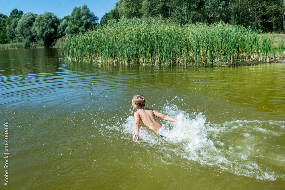 a boy bathes in a forest lake, jumps, in the water a boy bathes in a forest lake, jumps, in the water