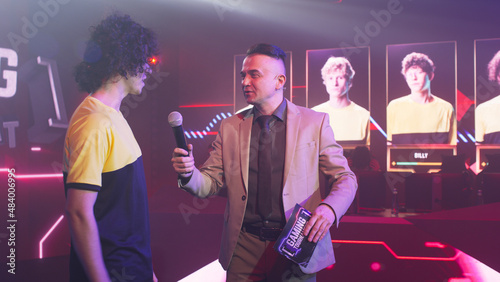 Tablou pe pânză Young cyber sportsman smiling and speaking to adult male announcer while standin