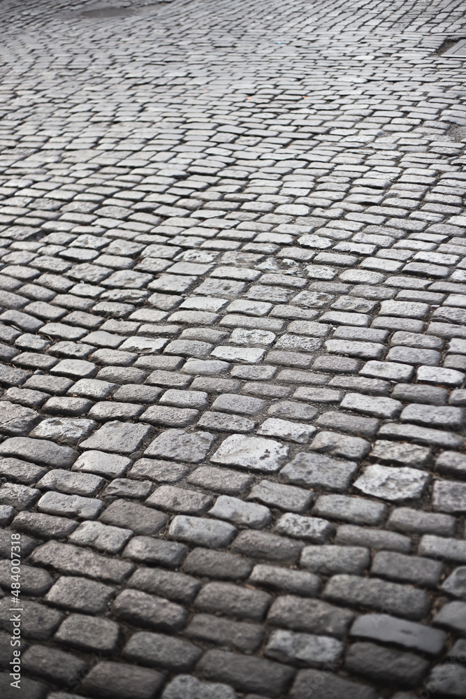Old stone paved road made of smooth paving stones polished by time - roadway and pavement
