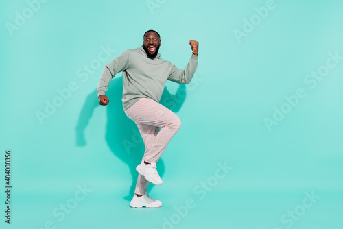 Full length body size view of cheery lucky attractive guy dancing rejoicing having fun isolated over bright teal turquoise color background
