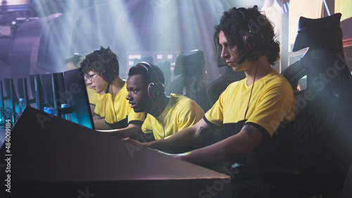 Angry esportsman gamer player breaking keyboard and touching head while expressing disappointment sitting near teammates after loss in professional video game match © Framestock