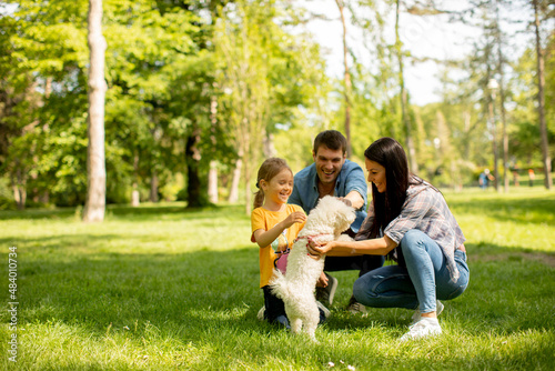 Happy family with cute bichon dog in the park