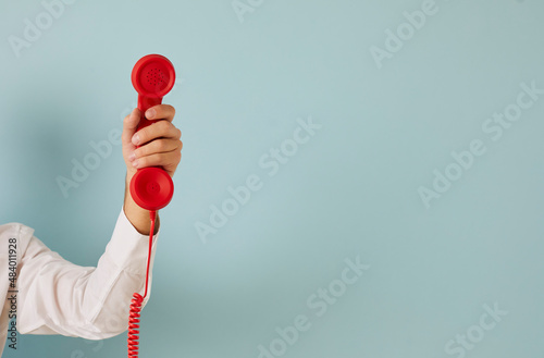 Man hand isolated on green studio background hold corded telephone for call center service ad. Male with wired phone express communication, make call for feedback or opinion. Copy space.