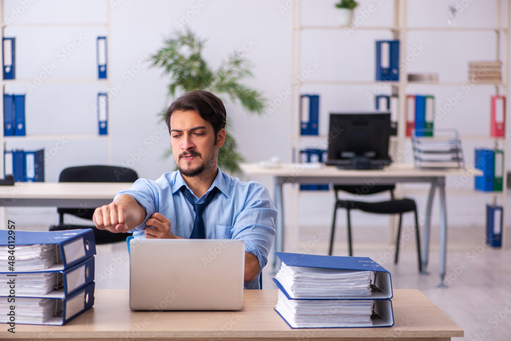 Young male employee and too much work in the office Young male employee and too much work in the office
