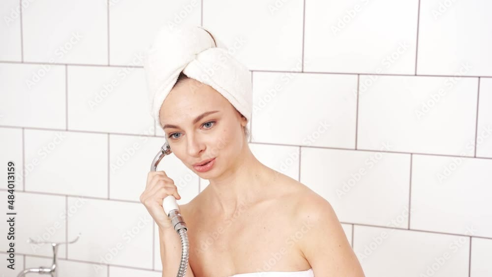 Young woman in bathroom talking by watering can. Luxury shower portrait. Lifestyle funny female person. Crazy rich lady vacation resort. Light brick background