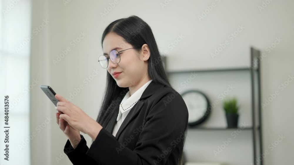 Smart asian woman business wearing glasses and black suit live in office, She use her mobile phone to chatting and looking for someone on footbridge. Slow Motion Shot. Smart asian woman business wearing glasses and black suit live in office, She use her mobile phone to chatting and looking for someone on footbridge. Slow Motion Shot.