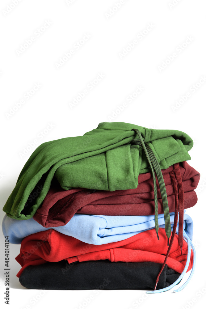 Stack of hooded sweatshirts and hoodie on white background. Casual wear. Copy space.
