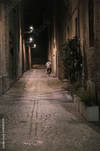 MAN ON BICYCLE IN AN ALLEY IN THE CITY CENTER OF PESARO