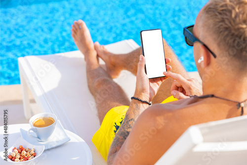 Man using cellphone by the pool, white screen mockup